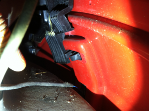 View of the left turn signal on the inside of the fender.  Only the gray clips and wires are visible.  The black part behind it is the EVSE charge door mounting bracket.